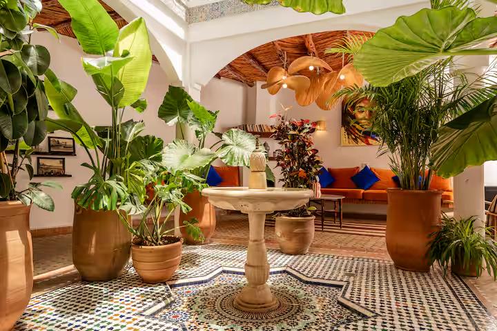 Moroccan riad courtyard with mosaic tiles, a fountain and plants